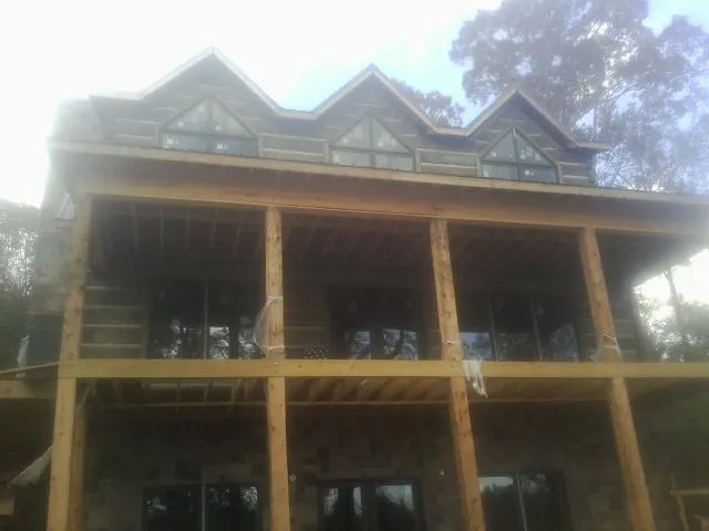 Dormers and porch framing on a large log home under construction — Roof Coating work by our crew in East Greenbush