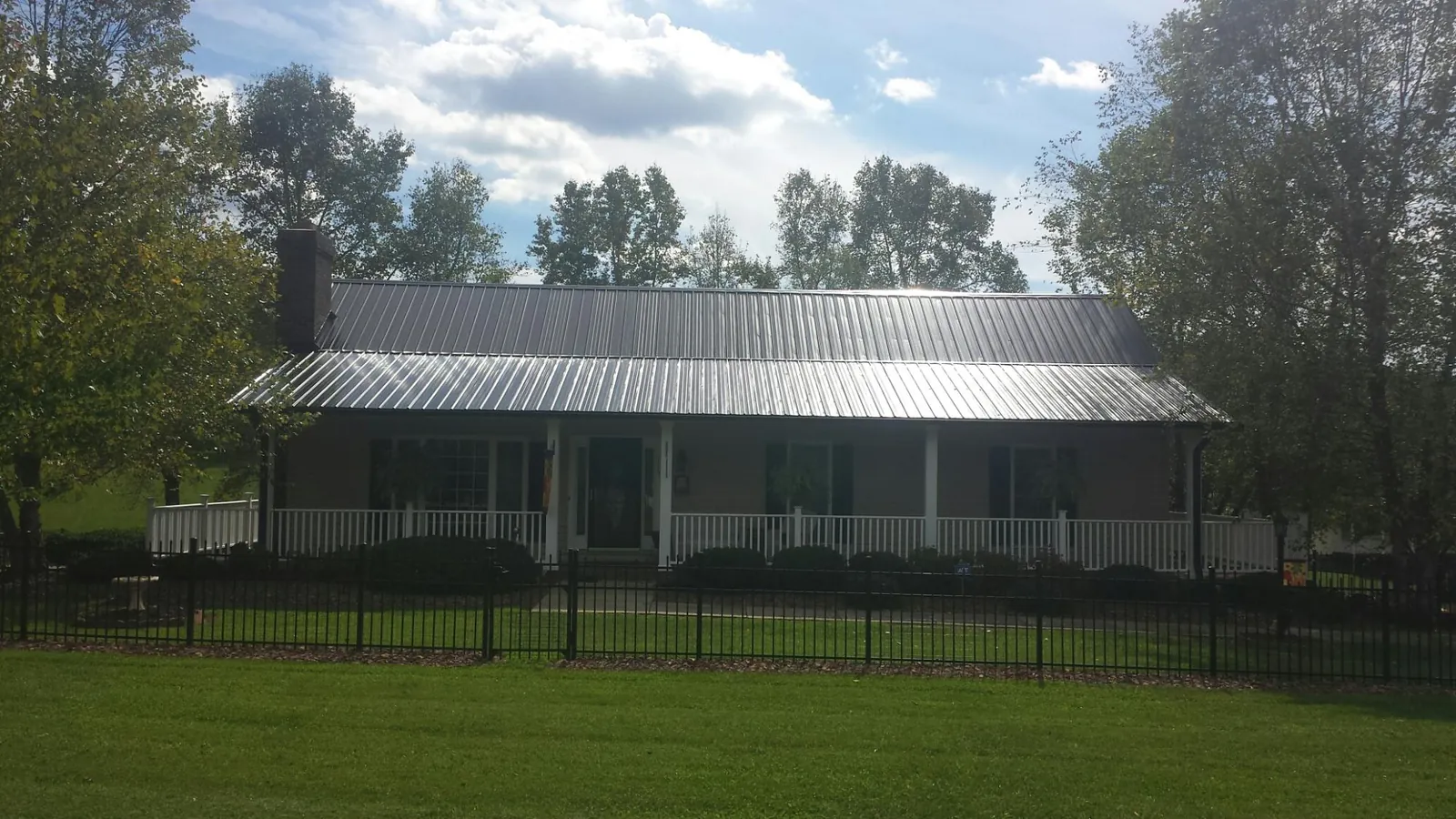 Gray metal roof on a brick ranch with a full width front porch — Gutter Guard Installation work by our crew in East Greenbush