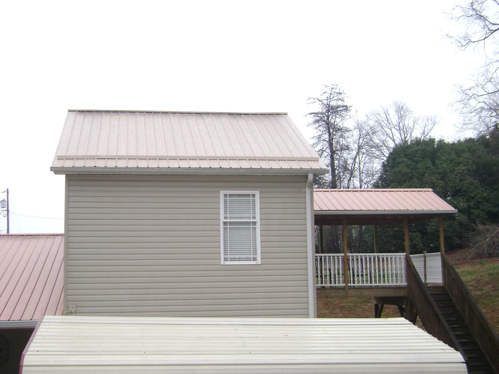 Tan metal roofs on a two story addition and attached porch, from a Roof Replacement job in East Greenbush