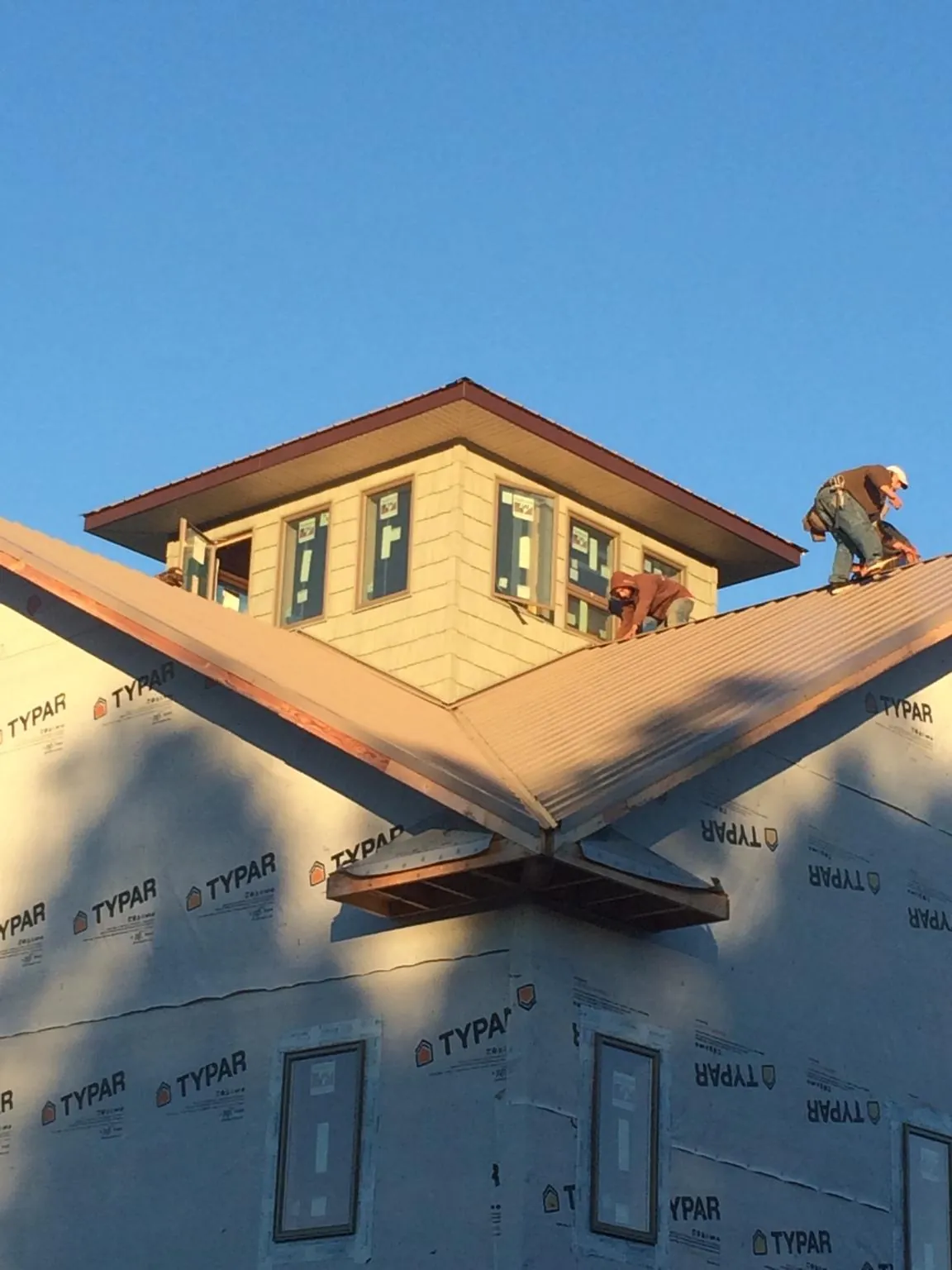 Roofers working around a rooftop cupola on a new metal roof at sunset — Roof Waterproofing in East Greenbush by Roofing Brothers